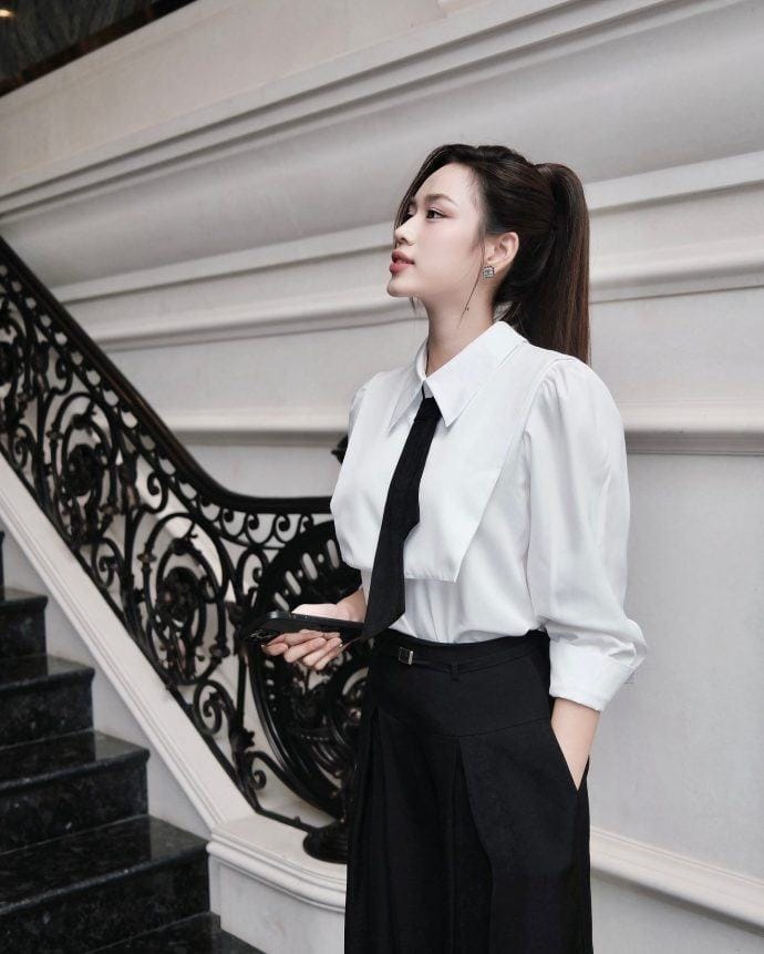 Đỗ Thị Hà diện áo sơ mi trắng và quần âu đen, phong cách công sở.