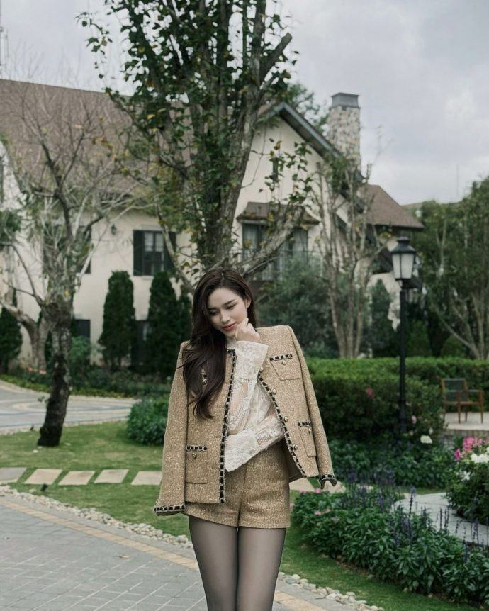 Đỗ Thị Hà diện áo cổ tròn và quần short đồng bộ, điểm nhấn là túi xách trắng.